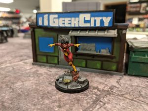 Spider Woman Miniature outside of tiny building
